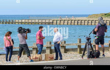 Gregg Wallace e Chris Bavin filmata per il mangiare bene per meno TV show su una spiaggia in riva al mare. Foto Stock