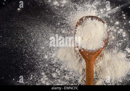 Farina bianca nel vecchio cucchiaio di legno. Vista superiore Foto Stock