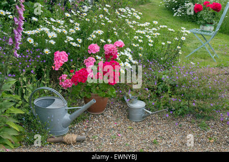 Giardino ancora vita gerani pedane. e innaffiatoi Foto Stock