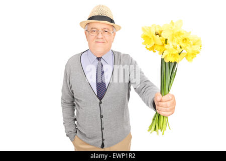 Riflessivo senior gentleman consegnando un mazzo di tulipani gialli verso la telecamera isolata su sfondo bianco Foto Stock