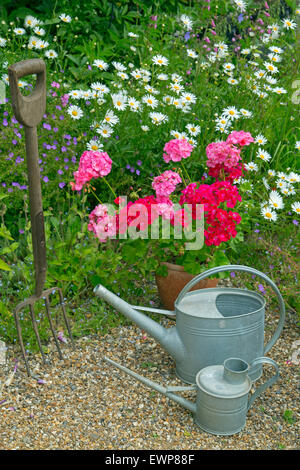 Giardino ancora vita gerani pedane. e innaffiatoi Foto Stock