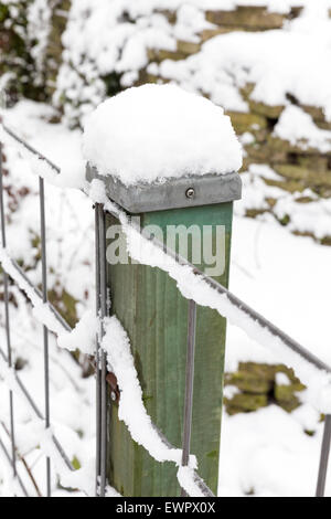 Neve sul palo di legno e una recinzione nella stagione invernale Foto Stock