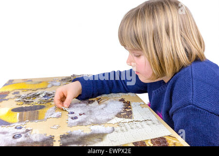 Giovane ragazza caucasica rendendo puzzle di gatti sulla tabella isolati su sfondo bianco Foto Stock