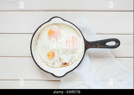 Uovo fritto in padella sullo sfondo di legno Foto Stock