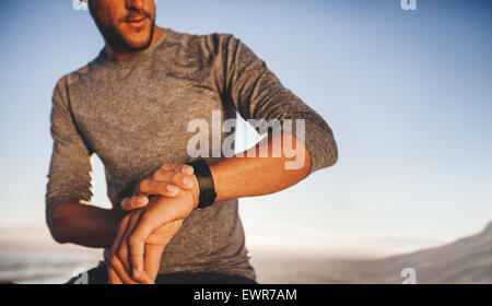 Atleta maschio controllo tempo mentre su outdoor training. Giovani runner controllando il tempo sul suo sport swatch Foto Stock