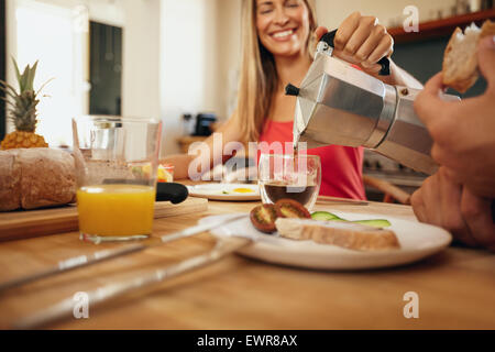 Piscina colpo di donna versando il caffè in una tazza. Donna sorridente mentre si serve la prima colazione all'uomo nella cucina di casa. Coppia giovane e Foto Stock