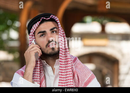 Giovane Imprenditore indossando un cappello tradizionale Dishdasha Foto Stock