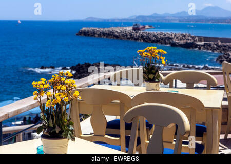 Taverna si affaccia sul mare con fiori sulla tavola Rethymno, Creta, Grecia Foto Stock