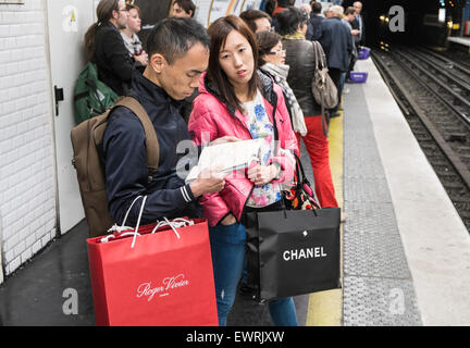 Parigi,Francia,francese,turisti cinesi,turistica, con,Chanel,branded,negozi,bag,a metro stazione ferroviaria a tarda notte dopo aver occupato il giorno di shopping. Foto Stock