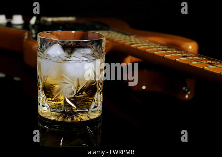 Un bicchiere di whiskey sulle rocce e la vecchia chitarra. Foto Stock