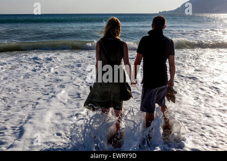 Creta meridionale, persone sulla spiaggia Grecia uomo donna coppia nel surf del mare persone che tengono le mani Foto Stock