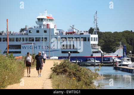 Walkers sul Solent strada tra Lymington e Keyhaven con il Wight traghetto di collegamento passante in background Foto Stock