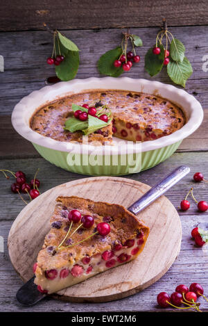 Clafoutis di ciliegio, tradizionale francese dessert. Pastella cotta pudding con ciliegie, spolverato con zucchero a velo e decorate con Foto Stock