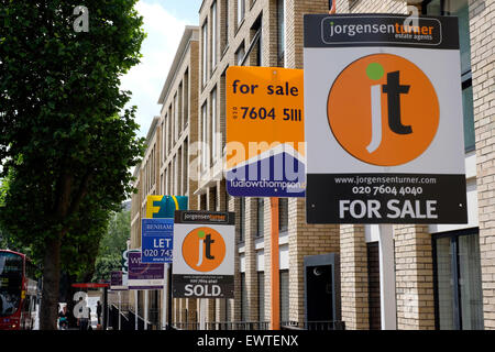 Diversi agenti immobiliari visualizzare i loro segni di vendita al di fuori di nuova costruzione appartamenti In Kilburn, Londra Foto Stock