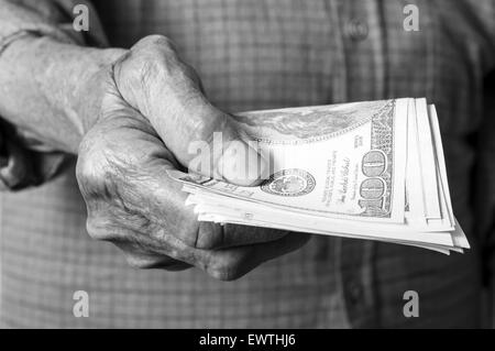 Il denaro di dollari negli anziani di mano. Messa a fuoco selettiva. Foto Stock