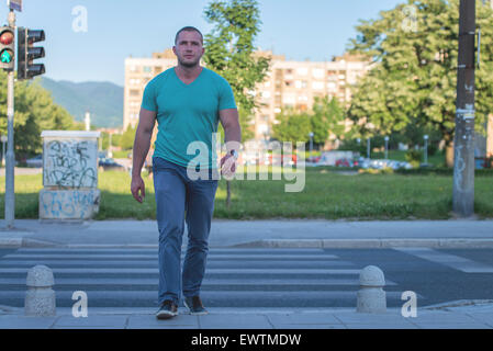 Giovane uomo a camminare sulle strisce pedonali Foto Stock