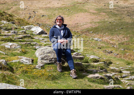 Donna seduta in campagna, Parco Nazionale del Distretto dei Laghi, Cumbria, England, Regno Unito Foto Stock