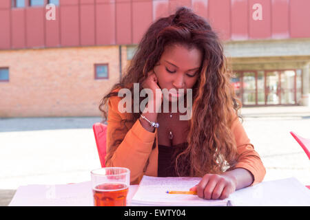 Giovane studente africano preparare gli esami presso una caffetteria locale Foto Stock