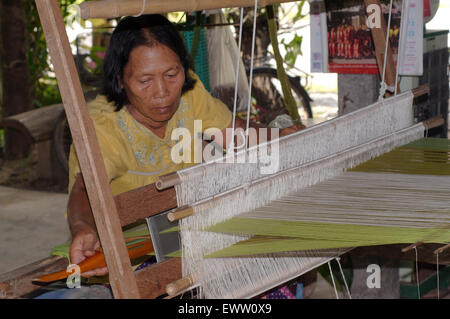 Un anziano Tai Dam donna che lavorano sul vecchio telaio in legno, Loei provincia, Thailandia Foto Stock