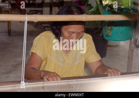 Un anziano Tai Dam donna che lavorano sul vecchio telaio in legno, Loei provincia, Thailandia Foto Stock