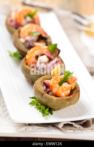 Cuori di carciofi farciti con frutti di mare. Sulla piastra bianca. Foto Stock