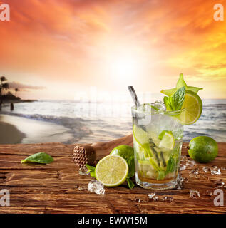 Il Mojito drink servito su tavole di legno. Blur spiaggia di tramonto come sfondo Foto Stock