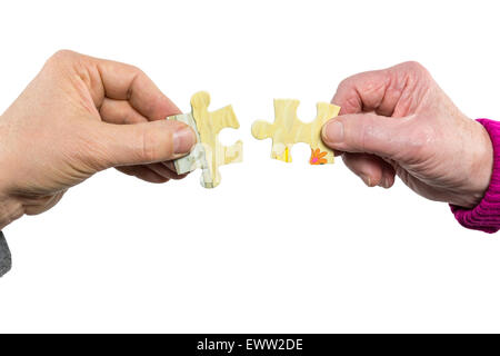 Due mani di uomo e di donna di giunzione di raccordo che unisce i pezzi del puzzle isolati su sfondo bianco Foto Stock