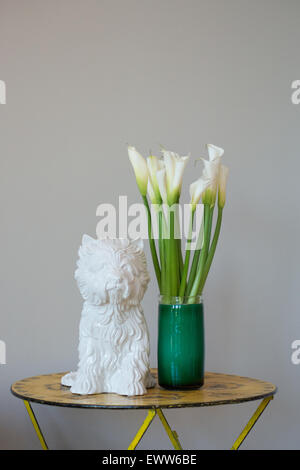 Bianco di ceramica "Puppy Vase' di Jeff Koons accanto a Calla Lilies in un vaso in vetro Foto Stock