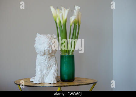 Bianco di ceramica "Puppy Vase' di Jeff Koons accanto a Calla Lilies in un vaso in vetro Foto Stock