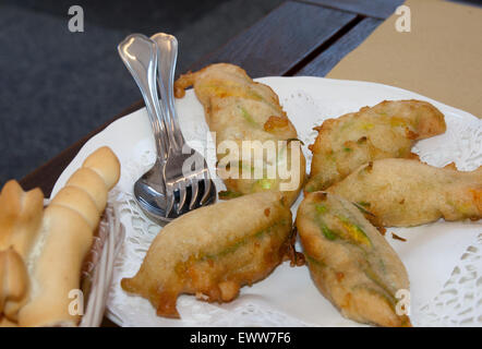 Piatti tipici della cucina italiana: fiori di zucca fritti in un piatto da portata e pane di ferrara Foto Stock