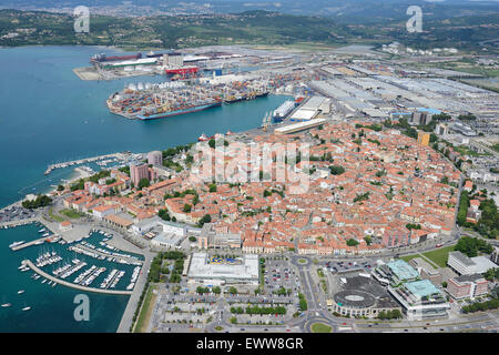 VISTA AEREA. Città medievale adiacente ad un moderno porto sulla costa adriatica. Capodistria (nota anche come Capodistria, il suo nome italiano), Slovenia. Foto Stock