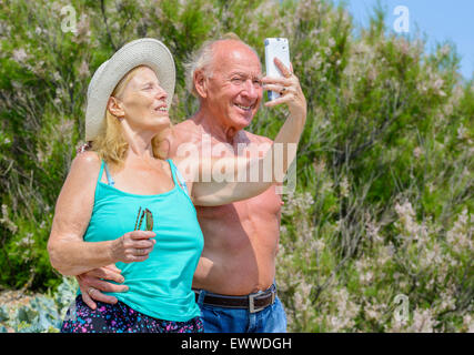 Coppia di anziani prendendo un selfie foto di se stessi in una calda giornata di sole in estate nel Regno Unito. Felice coppia di anziani. Coppia di mezza età godendo di estate. Foto Stock