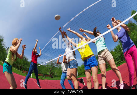 Attivi i ragazzi giocando a pallavolo sulla corte di gioco Foto Stock