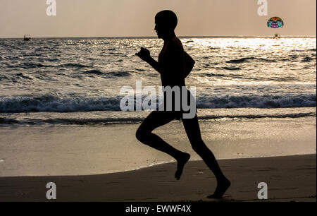 Al tramonto indiano jogging turistico e parasailing in background, a Baga Beach, stato di Goa, India, Asia. © Paul Quayle Foto Stock