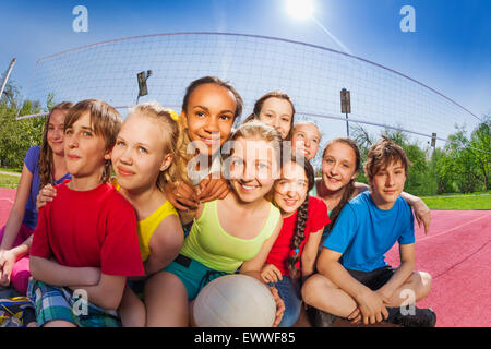 Gli amici siedono sulla partita di pallavolo corte sfera di trattenimento Foto Stock