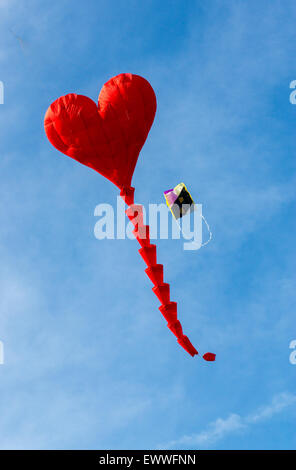 Un rosso a forma di cuore ad kite davanti a un cielo blu Foto Stock
