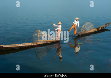 Pescatore birmano sulla barca di bambù per la cattura di pesce in modo tradizionale con la rete a mano. Lago Inle, Myanmar (Birmania) corsa destinat Foto Stock