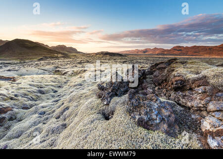 Campo di lava nella penisola di Reykjanes del sud dell'Islanda, shot come il sole che tramontava dietro alcune montagne Foto Stock