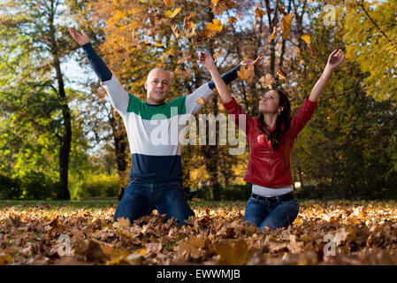 Amare giovane mescolare le foglie in autunno Park Foto Stock