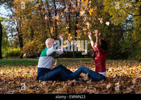 Amare giovane mescolare le foglie in autunno Park Foto Stock
