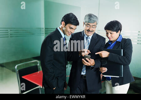 3 Indian business partner telefono cellulare discussione il dito puntato Foto Stock