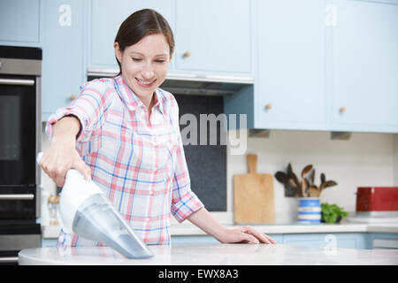 Donna di pulizia utilizzando cucina tenuto in mano aspirapolvere Foto Stock