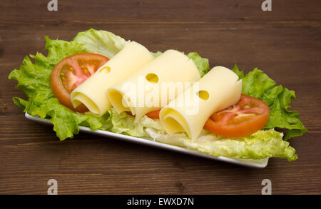 Fette di formaggio su insalata sul tavolo di legno Foto Stock