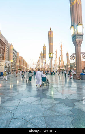 Pellegrini a piedi sotto ombrelloni giganti in moschea Nabawi composto. Foto Stock