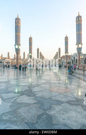 Pellegrini a piedi sotto ombrelloni giganti in moschea Nabawi composto. Foto Stock