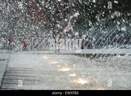 Persone che camminano davanti allo spray da una fontana illuminata a Berlino, in Germania Foto Stock