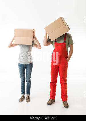 Donna e uomo in piedi e tenendo le scatole di cartone sulla parte superiore dei loro capi, su sfondo bianco. copia di spazio disponibile Foto Stock