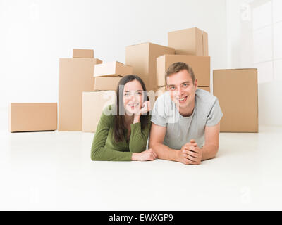 Felice coppia giovane seduto sul pavimento nella loro nuova casa Foto Stock