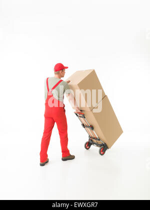 Vista posteriore di consegna uomo azienda spingere il carrello carico di scatole di cartone, su sfondo bianco. copia di spazio disponibile Foto Stock