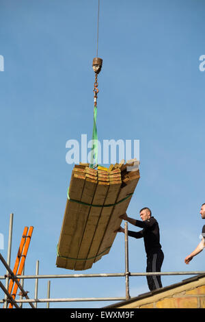 Il legname viene consegnato da una gru con un lavoratore builder sul ponteggio & Victorian casa a schiera roof top / nuova estensione dorma. Regno Unito Foto Stock